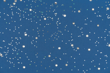 Blue background with silver sequins. Festive backdrop for your projects. Background for your product presentation. Christmas texture. Top view, copy space.