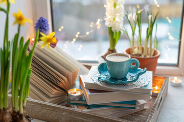 Coffee cup, open book, beautiful flowers, sparkle candles on window with bokeh. Reading and cup of...