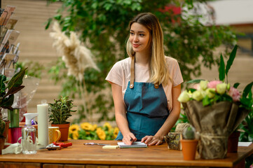 Florist writing in notebook while leaning against counter in a flower shop