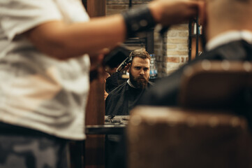 Young bearded man getting haircut by hairdresser
