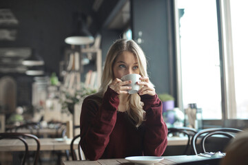 young woman in a cafe drinks coffee
