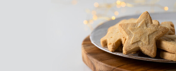 Christmas cookies large background. Different festive shape Scottish shortbread on the white plate with bokeh. Copy space