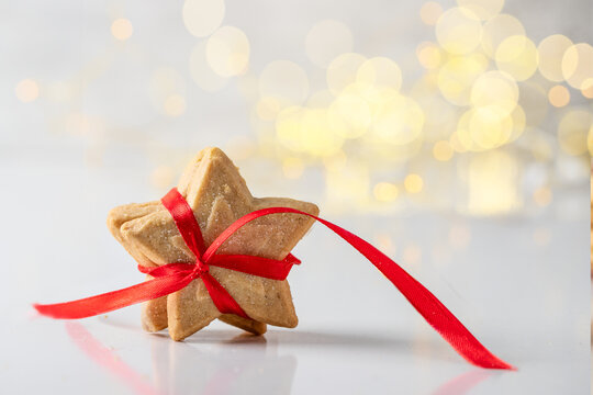 Star Shape Shortbread Cookies  With Red Ribbon On White Background With Gold Bokeh. Christmas Sweets Concept.