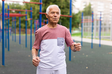 Obraz premium Senior man running on jogging track in nature. Healthy retirement lifestyle