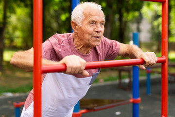 Sportive elderly man training on outdoor sports ground