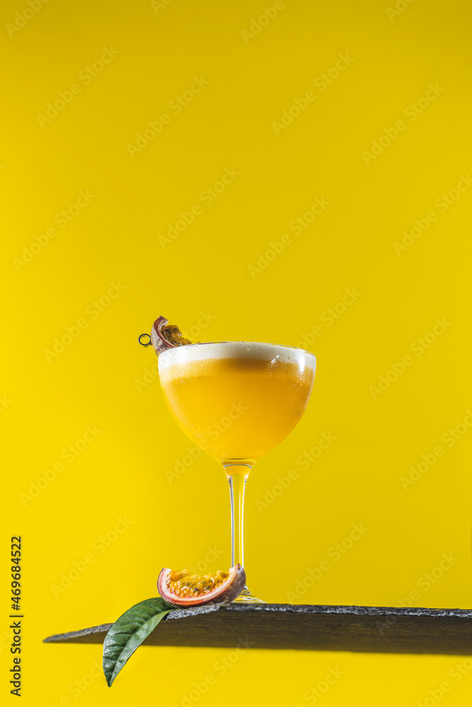 Wall mural glass of fresh passion fruit martini cocktail on bright yellow background