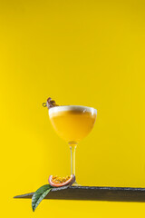 Glass of fresh passion fruit Martini cocktail on bright yellow background
