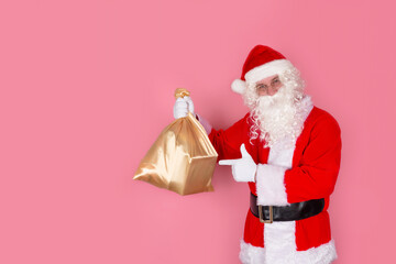 A close-up of Santa Claus with a gift bag, gifts and wishes for children on Christmas and New Year's Eve, isolated by a pink background