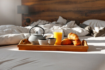 Breakfast in bed on a beautiful sunny morning, hot coffee, orange juice and fresh bread 