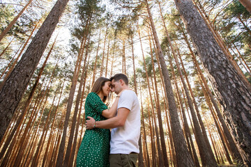 Horizontal view of young couple hiking on holidays in nature. Panoramic view of loving couple kissing at sunset in the forest. Countryside travel and people concept.