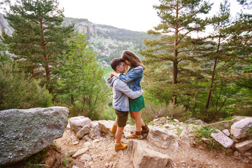 Side view of young couple in love hugging in the mountain surrounded by nature. Horizontal view of couple traveling in the black lagoon in Soria . People and travel in Spain concept.