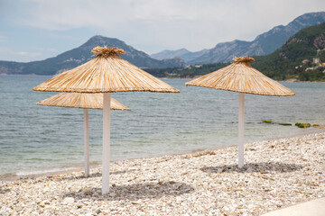 Beach with umbrellas and sun loungers by the sea on a sunny day, Montenegro.