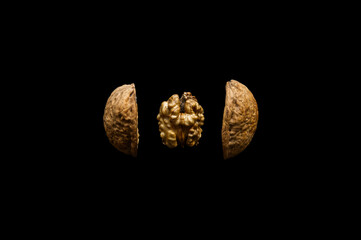 Open walnut split into pieces in space on black background. Background for t-shirt, print, cover.