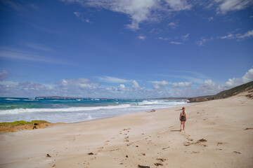 Girl walking on beach under clear blue sky at Portland Victoria Australia