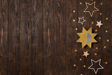Winter solstice day holiday, December 21. Sun, moon and golden stars symbol on rustic dark wooden background.