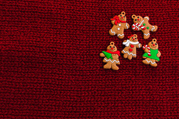 Gingerbread men on red knitted background. Christmas three decorations or New Year decorations. Flat lay. Cope space. Place for text. Top view. Holiday concept. Christmas greeting card.