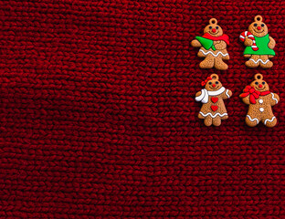 Gingerbread men on red knitted background. Christmas three decorations or New Year decorations. Flat lay. Cope space. Place for text. Top view. Holiday concept. Christmas greeting card.
