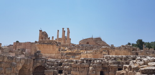 Fototapeta na wymiar Le célèbre site touristique jordanien - Jerash, avec ses constructions ou grandes portes à moitié démolies ou partielles, grande zone de vestige historique et de style romain ou égyptien, tas cailloux
