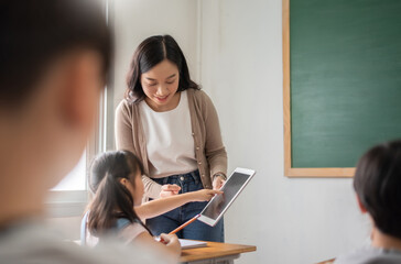 Asian Beautiful female teacher teaching Asian girl learning with digital tablet in classroom - Powered by Adobe