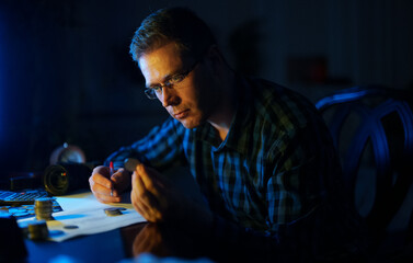 Male numismatist examines collection of coins.