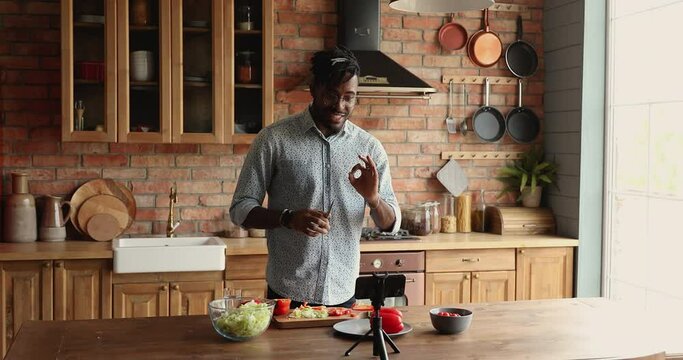 Handsome 30s African Man Standing In Kitchen Records On Cellphone New Food Videoblog, Teach Channel Subscribers To Cook Vegetarian Dish. Blogging, Healthy Lifestyle, Cooking Master Class Event Concept