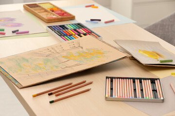 Artist's workplace with drawings, soft pastels and color pencils on table