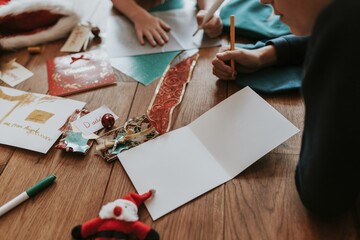 Kids writing Christmas cards on wooden floor