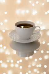 White cup with tea. Reflection. Blurred lights