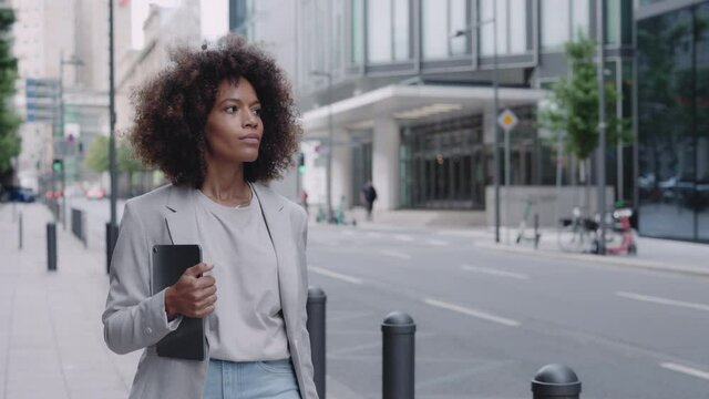 African american lady walking on street and carrying tablet