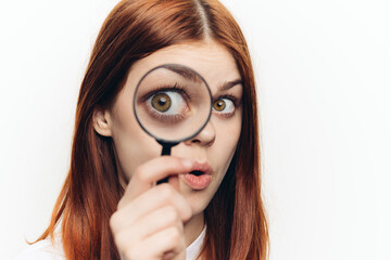 red-haired woman in a white shirt with a magnifying glass in her hands searching