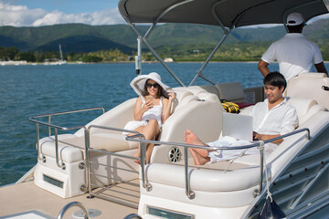 Handsome man and woman on deck of yacht with mobile phone and laptop