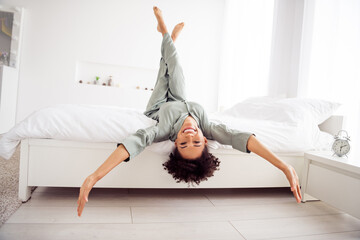 Portrait of attractive cheerful girl lying in bed having fun upside down good mood day at light home house indoors