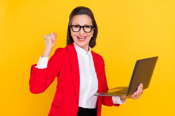 Photo of cute elder woman hand fist hold laptop wear cardigan eyewear isolated on yellow background