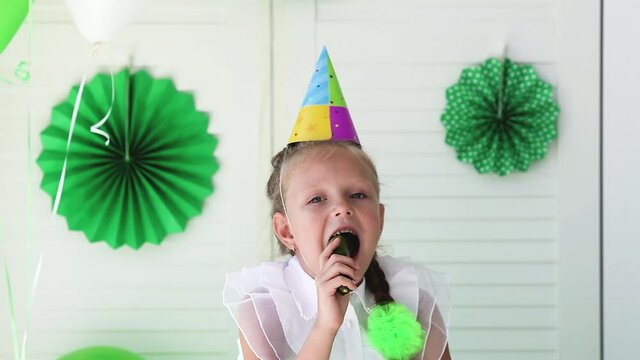 A little girl sings into a cucumber instead of a microphone and takes a bite of it. Birthday is my joy. Humor