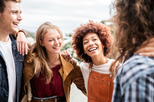 Group of multiracial best friends laughing together outdoor - Mixed race students having fun at college campus - Friendship, tourism, community, youth and university concept.