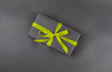 The gift is packaged in perfect gray on a gray background. The trend colors are yellow, gray. Copy space. View from above.