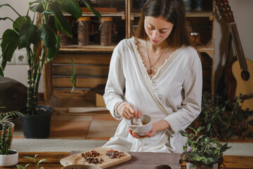 Cacao ceremony in atmospheric space with green plants and candles. Woman making ritual healthy drink from cocoa beans grind in pounder