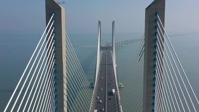 Lisbon, Portugal, aerial view, passing over in the center. of the Vasco da Gama bridge, on a foggy beautiful morning, during car traffic.
