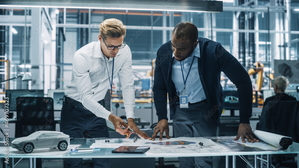 Poster two automotive engineers working in office at car factory. industrial designer shows conceptual elec