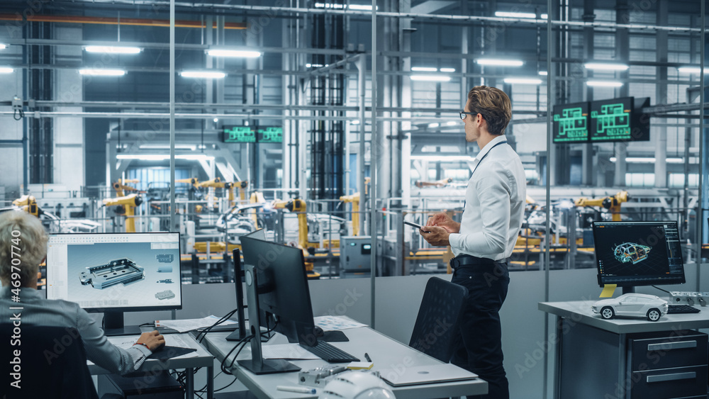 Poster handsome engineer in glasses and white shirt using tablet computer and looking out of the office at 