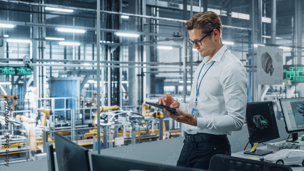 Aufkleber Handsome Engineer in Glasses and White Shirt Using Tablet Computer and Looking Out of the Office at a Car Assembly Plant. Industrial Specialist Working on Vehicle Design in Technological Facility.
