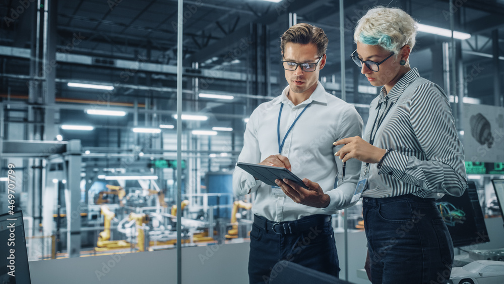 Poster male engineer and female industrial product designer discuss work while standing in office at a car 
