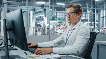 Confident Automotive Engineer Working on Desktop Computer in Modern Office at Car Assembly Plant. Industrial Project Manager Creating Sales, Finance and Marketing Reports at Vehicle Factory.