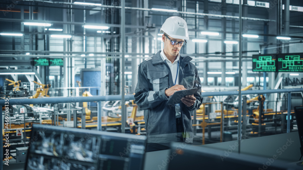 Aufkleber handsome engineer in uniform and hard hat using tablet computer at a car assembly plant. industrial 