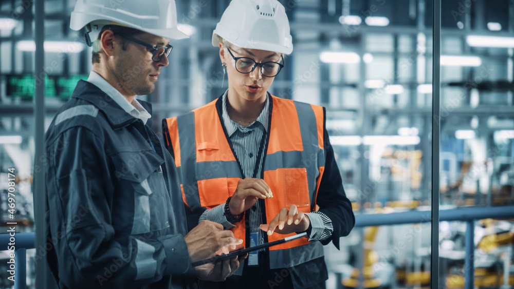 Poster male engineer and female industrial product designer discuss work while using tablet in office at a 