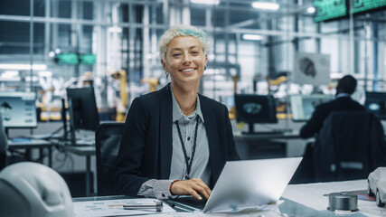 Portrait of a Happy Young Beautiful Female Engineer Sitting at a Desk, Using Laptop Computer in...