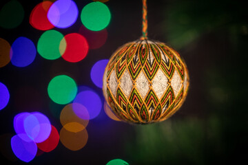 Christmas New Year's handmade toy hangs on a green spruce branch. Ball braided from threads