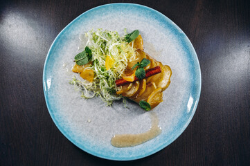 halibut fillet with fruit garnish on a blue ceramic plate
