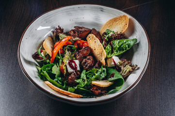 Warm salad mix with chicken liver and crouton. Restaurant food.