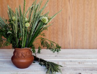 Bouquet of ears of grass and onion flowers on a wooden background.Village background.